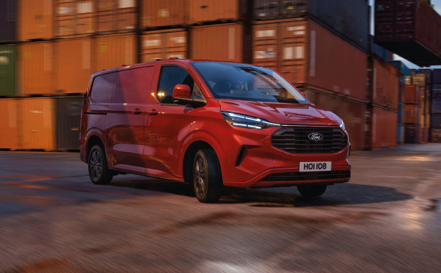 Bild på en röd Ford E-Transit Custom i fart snett framifrån